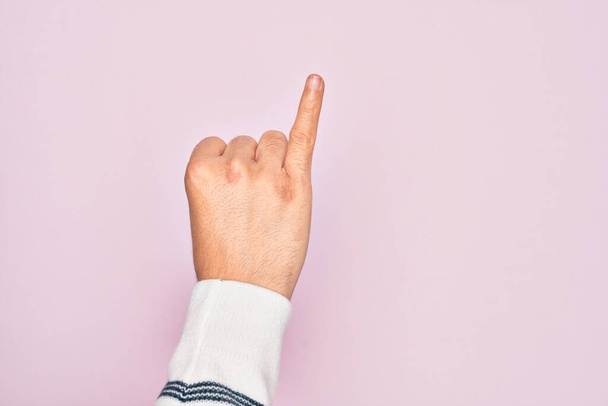 Mano de hombre joven caucásico mostrando los dedos sobre el fondo rosa aislado mostrando dedo meñique como compromiso promesa meñique, número uno - Foto, imagen