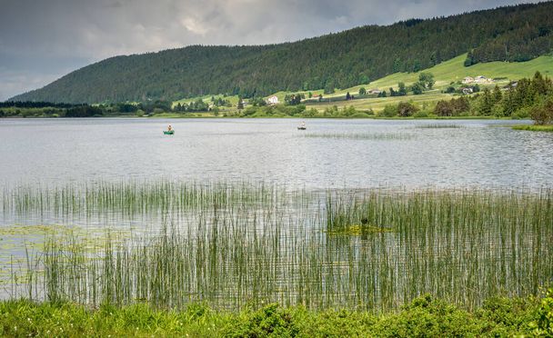 El lago Rousses con hierba y pescadores
 - Foto, Imagen