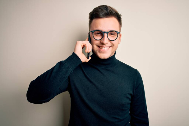 Jonge knappe blanke man met een gesprek praten op de smartphone met een vrolijk gezicht staan en glimlachen met een zelfverzekerde glimlach tonen tanden - Foto, afbeelding