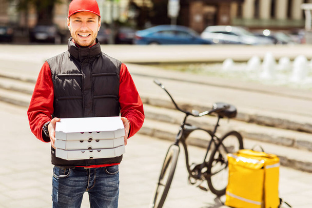Toimitus kuriiri tilalla Pizza laatikot hymyilevä kamera seisoo ulkopuolella - Valokuva, kuva