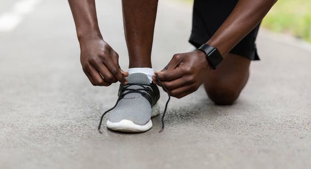 Gros plan de mec africain fixant ses chaussures de sport - Photo, image