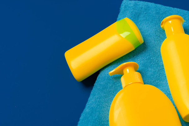 Bright yellow bottles of sunscreen product on dark blue paper background - Фото, изображение