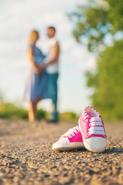 Pregnant woman and man baby shoes. Selective focus. nature. - Foto, immagini