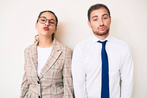 Beautiful couple wearing business clothes looking at the camera blowing a kiss on air being lovely and sexy. love expression.  - Photo, Image