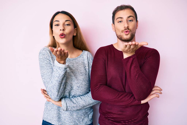 Beautiful couple wearing casual clothes looking at the camera blowing a kiss with hand on air being lovely and sexy. love expression.  - Photo, Image