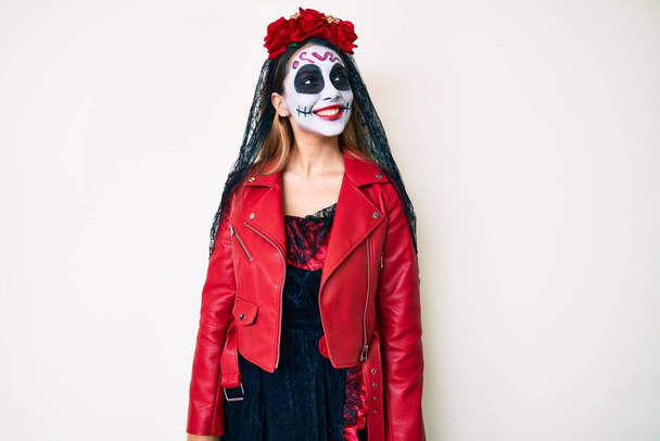 Woman wearing day of the dead costume over white looking away to side with smile on face, natural expression. laughing confident.  - Foto, Bild