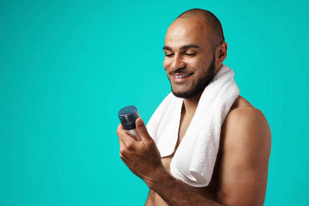 Happy african american man with towel holding shaving foam - Fotografie, Obrázek