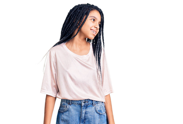 Jolie fille afro-américaine portant des vêtements décontractés regardant de côté avec le sourire sur le visage, expression naturelle. riant confiant.  - Photo, image