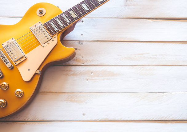Красива класична золота електрична гітара на білому дерев'яному столі, з копіювальним простором
. - Фото, зображення