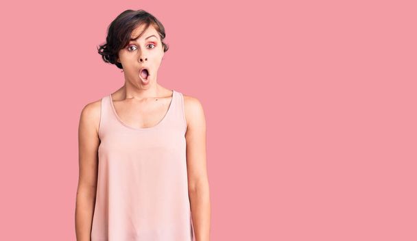 Beautiful young woman with short hair wearing casual style with sleeveless shirt afraid and shocked with surprise expression, fear and excited face.  - Photo, Image
