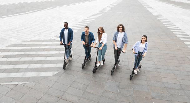 Cinco amigos que tienen un buen paseo en scooters de patada eléctrica
 - Foto, imagen