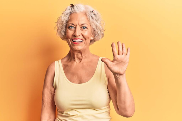 Donna anziana dai capelli grigi che indossa abiti casual mostrando e indicando con le dita il numero cinque mentre sorride fiducioso e felice.  - Foto, immagini