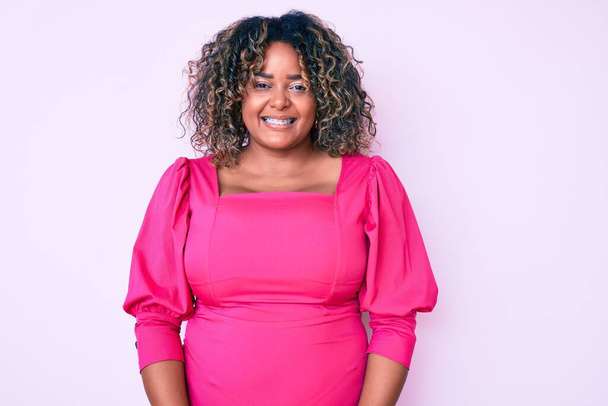 Jovem afro-americana plus size mulher vestindo roupas casuais olhando positivo e feliz de pé e sorrindo com um sorriso confiante mostrando dentes  - Foto, Imagem
