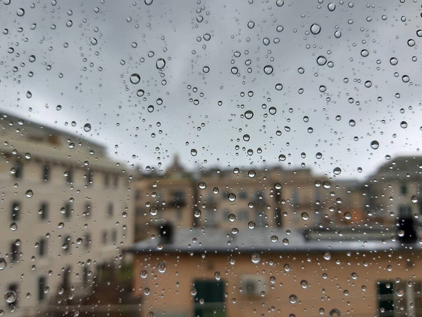 Krásná fotografie vodopádu nad oknem. Vnitřní panoramatický výhled na město po dešti. - Fotografie, Obrázek