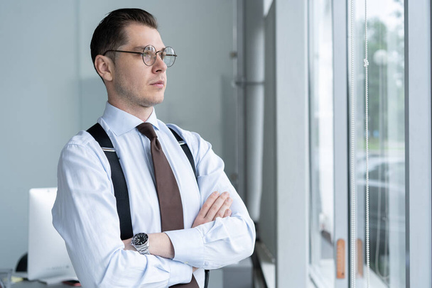 Portrait Of Businessman Standing By Window In Office. - Фото, зображення