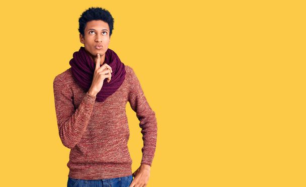 Nuori afrikkalainen amerikkalainen mies yllään rento talvi villapaita ja huivi ajattelu keskittyi epäilystä sormella leuka ja etsivät ylös ihmetellen  - Valokuva, kuva