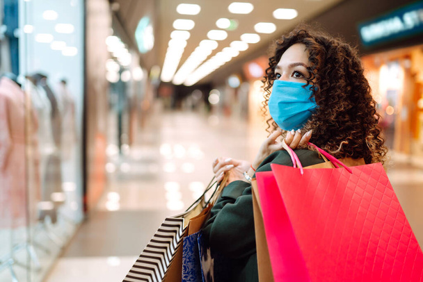 Young woman in medical face mask after shopping during coronavirus pandemic. Covid-2019. - Valokuva, kuva