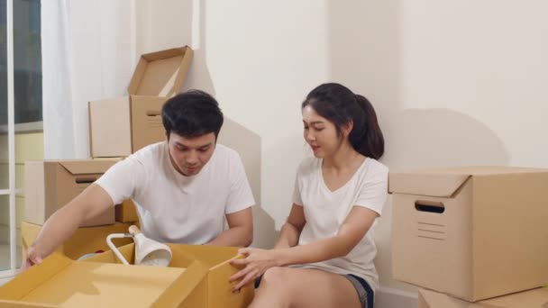 Szczęśliwa azjatycka młoda para kupiła nowy dom. Koreański rodzina otwarcie rozpakowywanie kartonowe pudełka i łatwy i szybki handel usługi dostawy do dużego nowoczesnego domu. Nowe nieruchomości mieszkalne, kredyty i hipoteki - Materiał filmowy, wideo