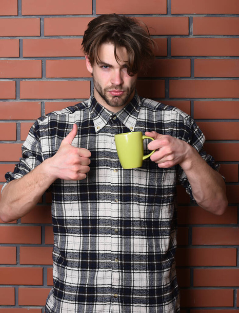 handsome guy holding cup on brick wall background - Φωτογραφία, εικόνα