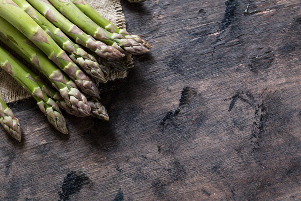 Green Asparagus. Bunches of green asparagus on a dark wooden rustic background - Photo, Image
