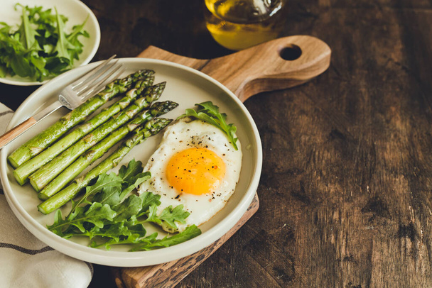 Healthy homemade breakfast with asparagus, fried egg and arugula. quarantine healthy eating concept. keto diet - Photo, Image
