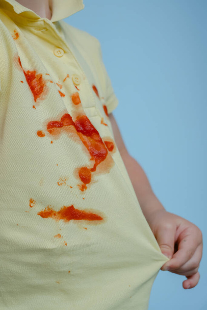 il bambino tira una T-shirt con macchie da ketchup - Foto, immagini