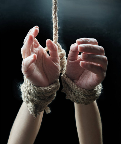黒い背景に荒縄で縛られた被害者の女性の手。暴力の概念を悪用しないで - 写真・画像