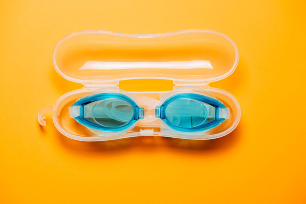 Niebieskie okulary kąpielowe, z gumowym paskiem w plastikowej walizce, na żółtym tle. Nikt, koncepcja produktu - Zdjęcie, obraz