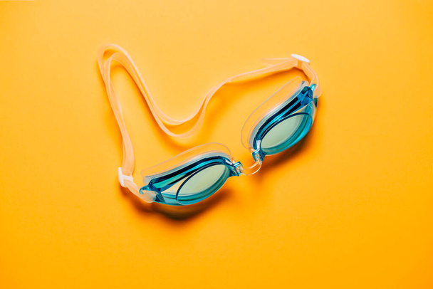 Синие купальные очки с резиновым ремешком на желтом фоне. Никто, концепция продукта - Фото, изображение