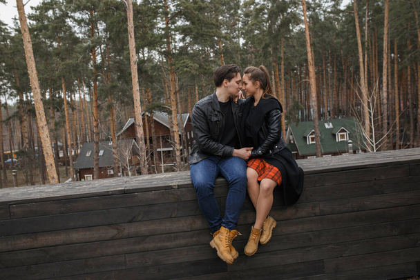 junges Paar in schwarzen Jacken umarmt und posiert im Wald. - Foto, Bild