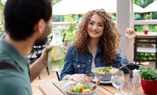 Happy couple sitting outdoors on terrace restaurant, talking. - Zdjęcie, obraz