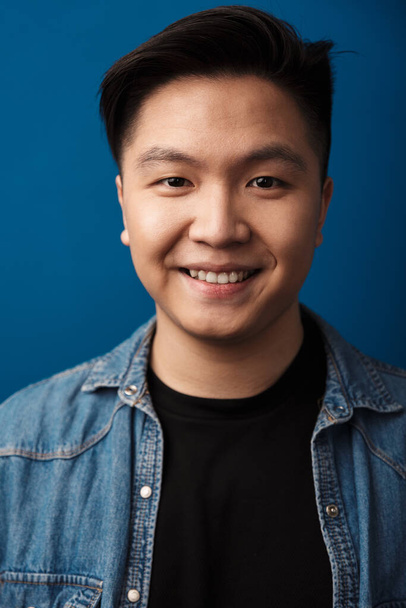 Image of pleased handsome asian man smiling and looking at camera isolated over blue background - Фото, зображення
