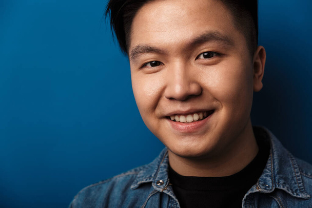 Image of pleased handsome asian man smiling and looking at camera isolated over blue background - Fotoğraf, Görsel