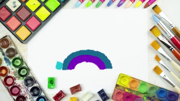 regenboog tekening animatie op een platte lay schilderij achtergrond met wit papier blad, palet van aquarelverf, borstels, kleurrijke krijt krijtjes, kinderen achtergrond bovenaanzicht - Video