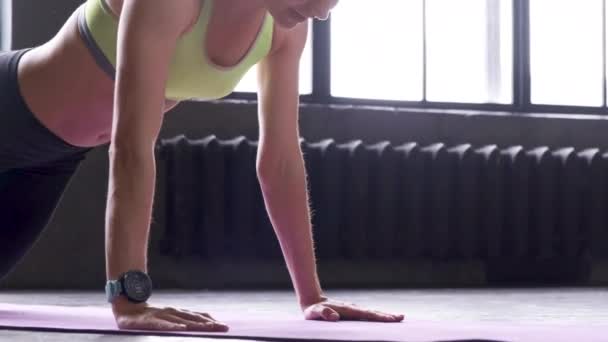 Felismerhetetlen vonzó fiatal nő sportmelltartóban és rövidnadrágban fekvőtámaszt csinál egy edzőteremben..  - Felvétel, videó