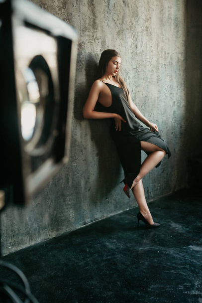 Portrait of caucasian brunette woman wearing in the black dress and posing in the loft studio.  - Foto, imagen