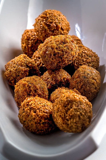 Falafel balls on a white background. Falafel is a traditional Middle Eastern food, commonly served in a pita.Vertical image. - Fotó, kép