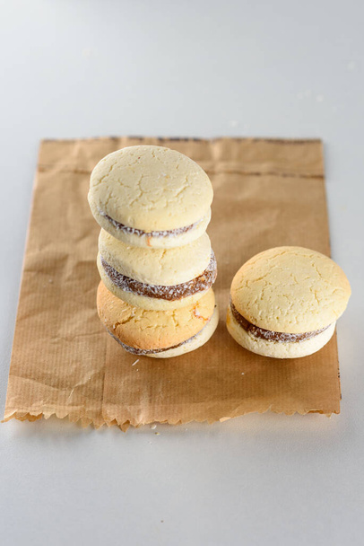 Delicious Argentinian cookies alfajores with cream dulce de leche on the table on paper bag, plastic free. Close up white vanilla macaroons on white background. French delicate dessert for breakfast. - Foto, Imagem
