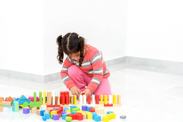 Thuis spelletjes voor kinderen. Creatief kinderspel met houten speelgoed bouwstenen in huis tijdens covid 19. - Foto, afbeelding