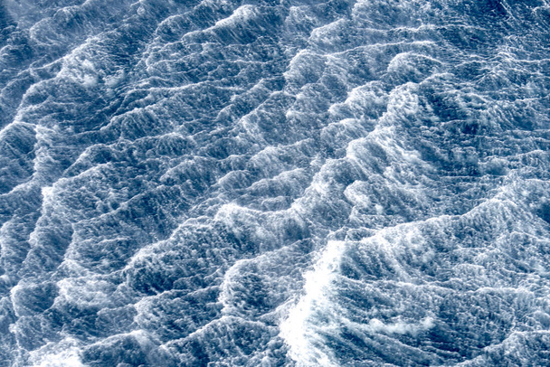 Ροή ταραχών του κύματος που δημιουργείται από κακές καιρικές συνθήκες πάνω από την επιφάνεια του θαλασσινού νερού. - Φωτογραφία, εικόνα