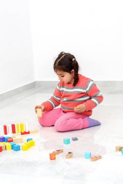 Kotipelejä lapsille. Luova lapsi leikkiä puinen lelu rakennuspalikoita kotona aikana coronavirus. - Valokuva, kuva