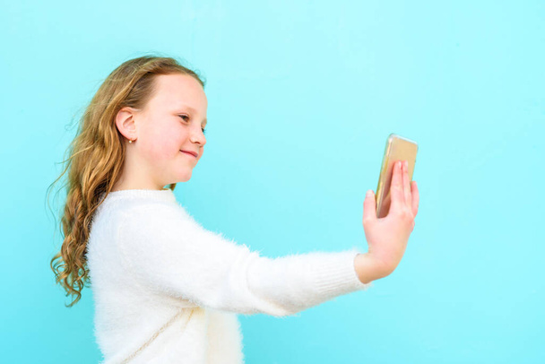 Retrato de chica alegre fresco que tiene video-llamada sosteniendo el teléfono inteligente en la mano disparando selfie en la cámara frontal
. - Foto, imagen