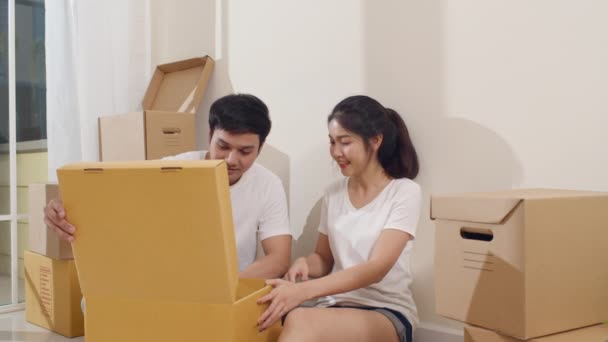 Happy Asian young couple bought new house. Korean family opening unpacking cardboard boxes and easy and fast service commerce delivery into big modern home. New real estate dwelling, loan and mortgage - Footage, Video