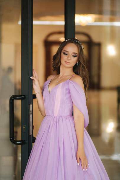 Young woman in beautiful purple dress posing to photographer by the restaurant - Photo, Image