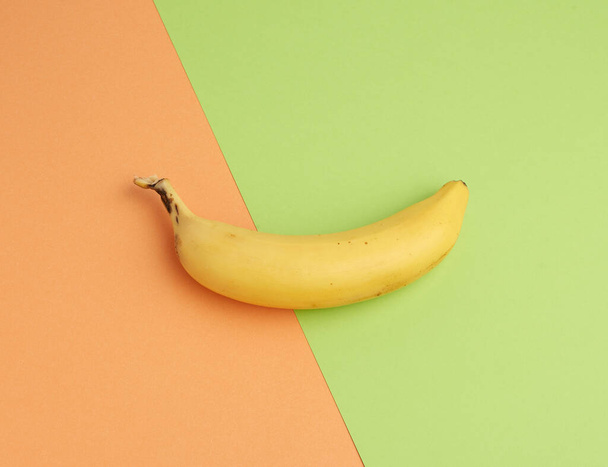 ripe yellow banana on a colored background, top view, close up - Zdjęcie, obraz