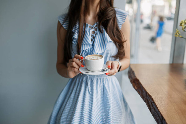 hermosa joven posando en una cafetería. sosteniendo una taza de café. primer plano
 - Foto, Imagen