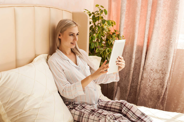 terhesség, technológia, az emberek és a várakozás koncepció - boldog terhes nő tabletta számítógép az ágyban otthon - Fotó, kép