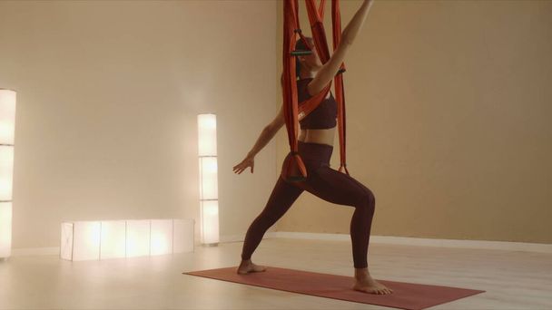 Meisje dat yoga doet met bandjes in de klas. vrouw doet krijger poseren op yoga mat - Foto, afbeelding