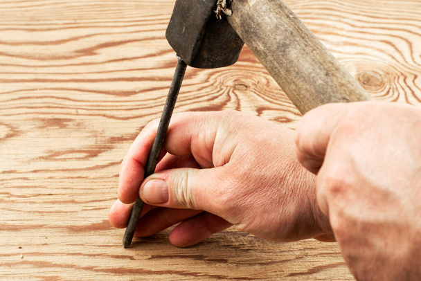 the man hammers a nail into a damaged surface - Fotografie, Obrázek