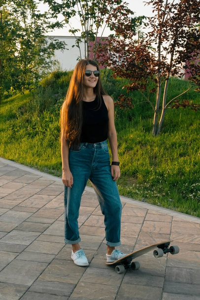 young beautiful woman wearing sunglasses and casual clothes riding skateboard - Valokuva, kuva